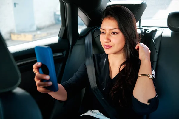 Молодая латинская бизнесвумен, использующая смартфон в своей машине — стоковое фото