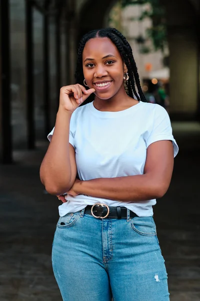 Örgülü Latin kadının portresi. Kameraya bakıyor ve gülümsüyor.