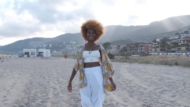 Молодая красивая африканская американка на пляже с закатом позади нее — стоковое видео