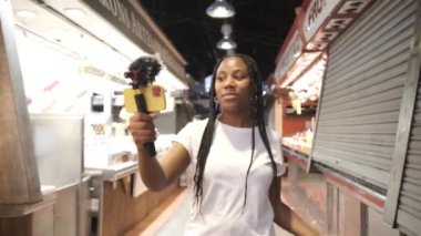 Genç Afro-Amerikan etkileyicisi akıllı telefon kullanarak canlı yayın yapıyor.