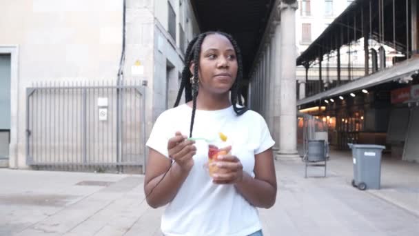 Ung afrikansk amerikansk kvinna äta hälsosam frukt utomhus — Stockvideo