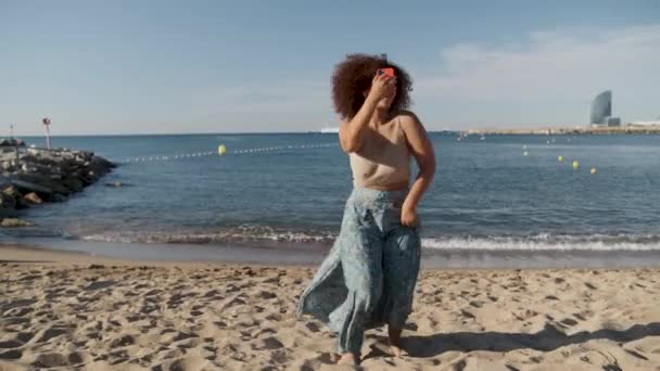Νεαρή γυναίκα σγουρά μαλλιά χορεύει για ιογενή βίντεο στην παραλία της Βαρκελώνης — Αρχείο Βίντεο