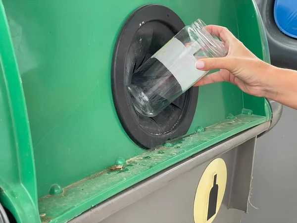Mãos de uma mulher reciclando vidro em um containger - conceito de sustentabilidade — Fotografia de Stock