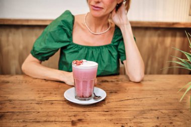 Arkasında tanınmayan bir kadın olan pembe bir smoothie.