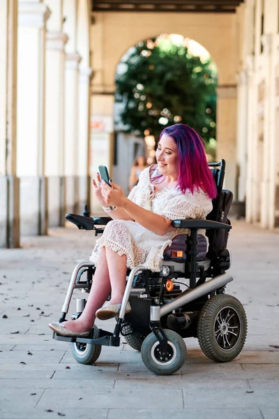 Una mujer con discapacidad en una silla de ruedas usando un smartphone para desplazarse por la pantalla —  Fotos de Stock