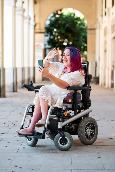 Mujer en silla de ruedas usando smartphone para videoconferencia - streaming —  Fotos de Stock