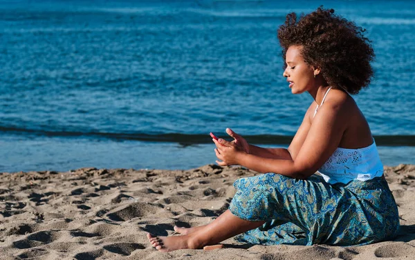 Joven mujer real con curvas en la playa con teléfono inteligente —  Fotos de Stock