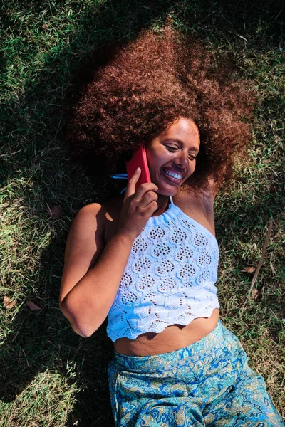 Молодая расслабленная кривая афро женщина с помощью смартфона — стоковое фото