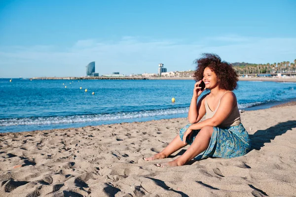 Een jonge vrouw die een smartphone gebruikt op het strand van Barcelona — Stockfoto