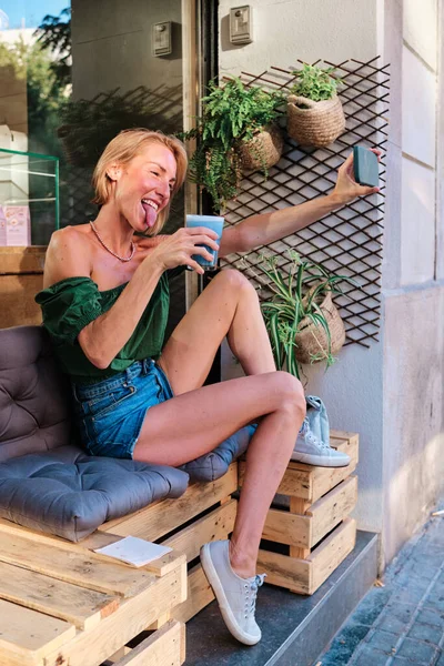 Šťastná dospělá žena předstírající se zdravým pitím a smartphonem — Stock fotografie