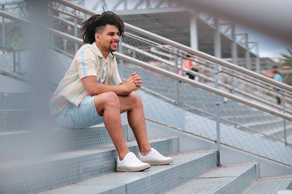 Giovane uomo latino con i capelli ricci sorridente e guardando fuori dalla fotocamera — Foto Stock