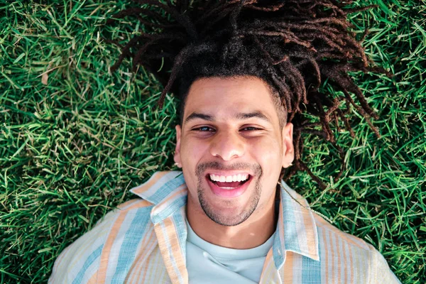 Close-up van grappig latijn man met krullend haar liggend op het gras — Stockfoto