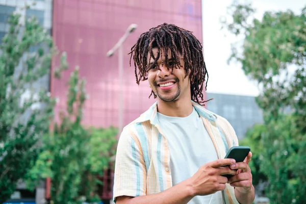 Latin férfi néz félre a kamera és mosolyog a városra — Stock Fotó