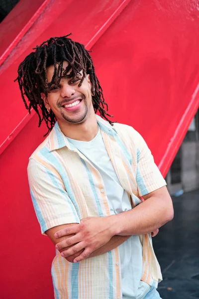 Giovane uomo latinx fiducioso con capelli ricci guardando la fotocamera e sorridente — Foto Stock