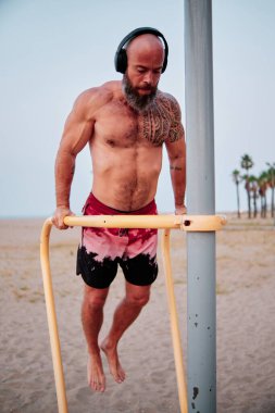 Sporcu adam sahilde barfiks çekerken beden eğitimi yapıyor..