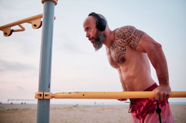 Sahilde barfiks çekerken antrenman yapan sporcu..