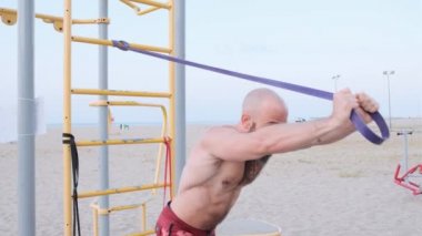 Plajda lastik bantla atletizm eğitimi almış. Jimnastik konsepti.