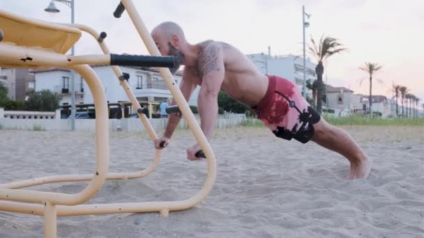 Sportowiec robi pompki z równoległymi barami w parku sportowym na plaży. Koncepcja sportu, siły i motywacji. — Wideo stockowe