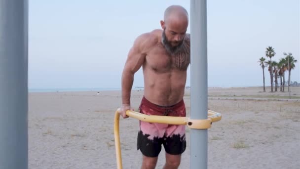 Oldalnézet egy atléta férfi gyakorló calisthenics miközben chin-up a strandon. Sport és fitness életmód koncepció. — Stock videók