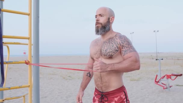 Fitness homme faire de l'exercice de calisthénique avec un élastique de résistance à la plage. Concept sportif. — Video