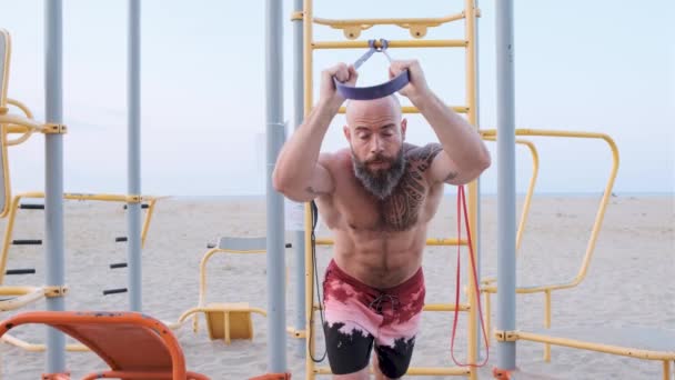 Allenamento atletico uomo con un elastico di resistenza in spiaggia. Concetto di allenamento alisthenico. — Video Stock