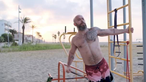 Fitness człowiek robi ćwiczenia gimnastyczne pleców z gumką oporową na plaży. Koncepcja sportu. — Wideo stockowe