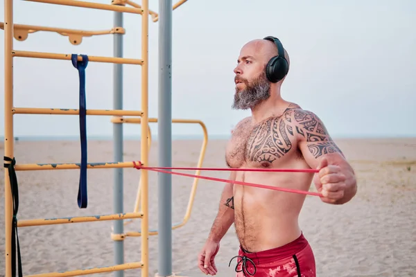 Jimnastik istasyonunda lastik bantla antrenman yapan bir fitness adamı..