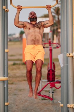 Yatay çubukta barfiks çekerken egzersiz yapan adam.