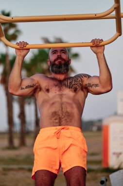 Açık havada egzersiz yaparken barfiks çeken güçlü bir adam..