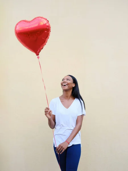 Femme afro-américaine joyeuse tenant un ballon de coeur rouge à l'extérieur. — Photo