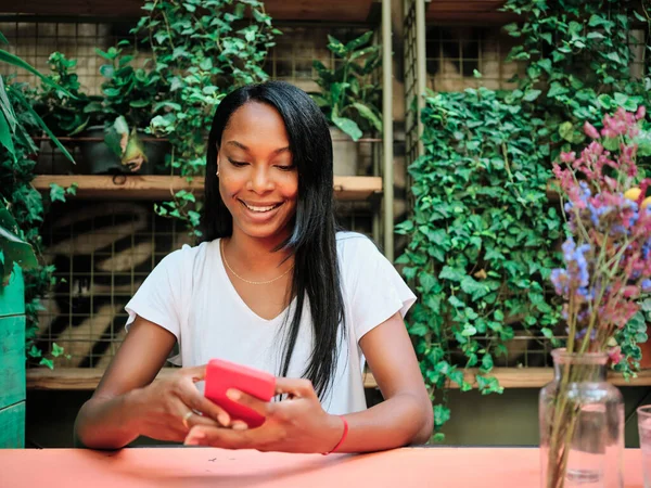 Femme utilisant un téléphone portable assis dans un restaurant ou un café jardin. — Photo