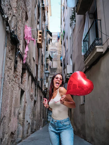 빨간 심장을 들고 거리에서 풍선 모양을 하고 있는 젊은 여자. — 스톡 사진