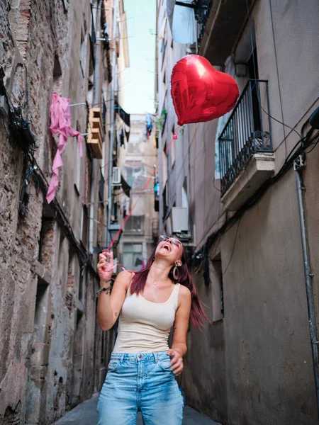 Vrolijke vrouw houdt een rode hart ballon buiten. — Stockfoto