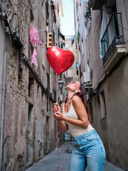 Femme avec un ballon rouge en forme de coeur à l'extérieur dans la rue. — Photo
