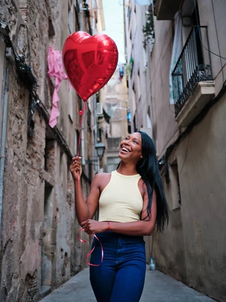 Jeune femme tenant un ballon de coeur à l'extérieur dans la rue. — Photo