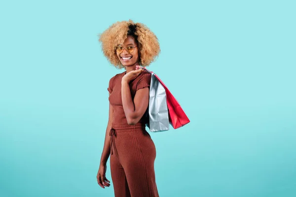 Улыбающаяся афро-женщина с разноцветными бумажными пакетами на изолированном фоне. Концепция распродаж "черной пятницы". — стоковое фото