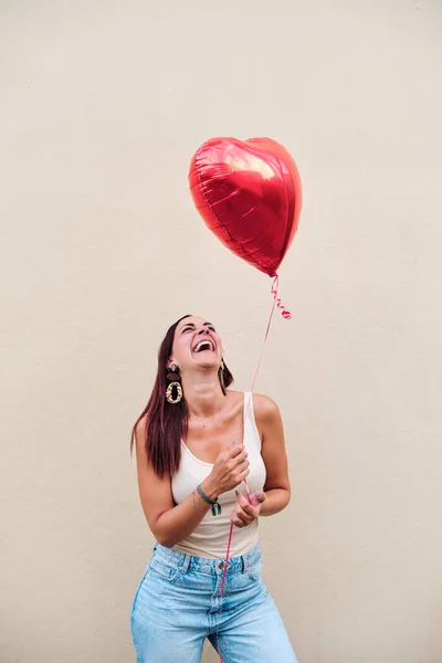 Mujer joven sonriendo mientras sostiene un globo cardíaco al aire libre. —  Fotos de Stock