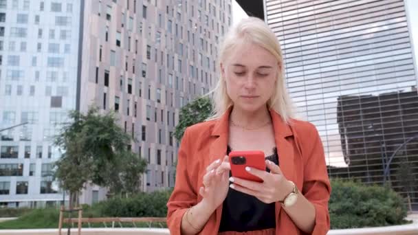 Молода біла жінка використовує свій смартфон у діловому районі - бізнес-концепція кишеньковий кліп — стокове відео