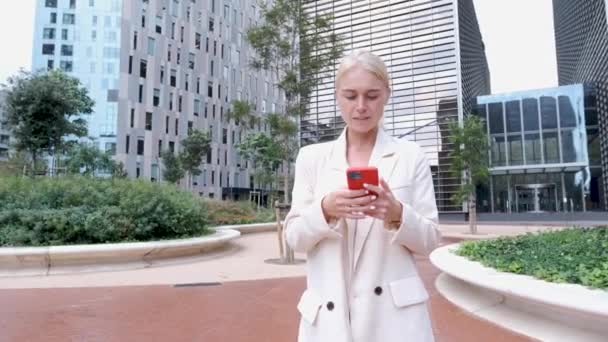 Молода ділова жінка смс і використовує смартфон у фінансовому районі — стокове відео