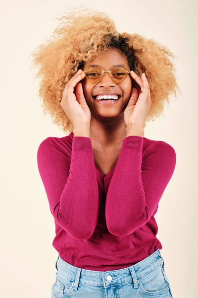 Joven afro mujer usando gafas de sol y sonriendo mientras está de pie sobre un fondo aislado. —  Fotos de Stock