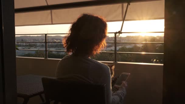 Donna irriconoscibile con problemi di salute mentale da sola al balcone al tramonto a giocare con il suo gatto — Video Stock