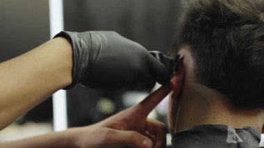Berberler müşterilerinin saçını tıraş etmek için saç makasıyla siyah eldiven veriyorlar. Saç kesim sürecini gösteren ayrıntılı çekim