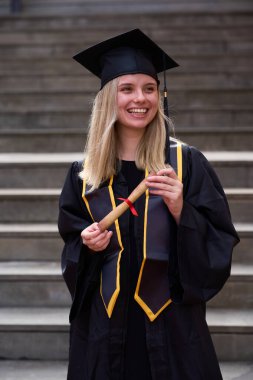 Diploma alan genç bir kadın, mezuniyeti kutluyor. Eğitimini tamamladıktan sonra mutluluğu ve başarıyı hissetmek.