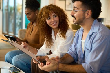 Çeşitli iş arkadaşları proje çalışmaları hakkında görüşüp tartışırken, bir kadın belgeyi bir panoya not ediyor - mali, sigorta ve hukuki danışmanlık