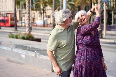 Yaşlı çift emekliliğin tadını çıkarıyor, şehir sokaklarında dans ediyor ve gülüyor, mutluluk, sevgi ve birlikteliği ifade ediyorlar.