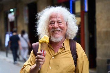 Gülümseyen, kıvırcık saçlı, elinde dondurma külahıyla şehirde yürürken tatlı bir ziyafetin tadını çıkaran son sınıf öğrencisi.