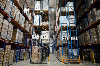 Modern endüstriyel soğuk zincir depolama tesisinde uzun metal raflarda depolanan paketlenmiş ürünler.