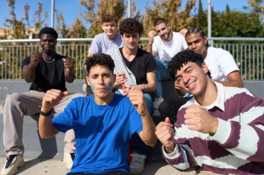 Çeşitli gençler tribünde oturup coşkuyla tezahürat yapıyor ve bir etkinliği desteklerken takım ruhunu gösteriyorlar.