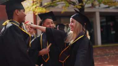 Mezuniyet töreninde birbirlerine sarılıp tebrik eden genç öğrenciler. Akademik başarı ve başarıyı kutlayan arkadaşlar