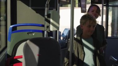 Aydınlık ve güneşli bir yaz gününde otobüsten inen oğlu ve yaşlı kadınlarla birlikte bir anne de dahil olmak üzere çeşitli yolcular.